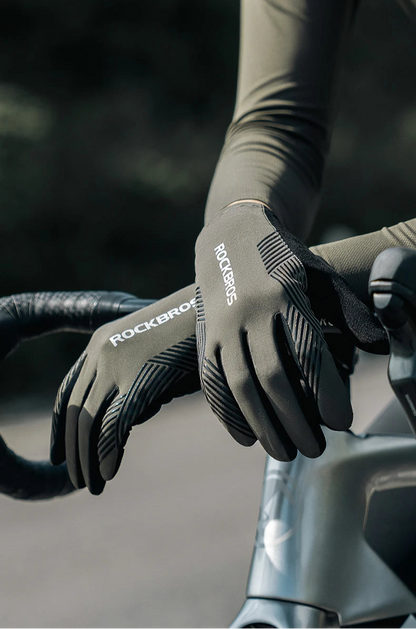 Person wearing black gloves with 'RockBros' branding on a bicycle handlebar.